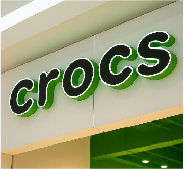 Letrero de tienda Crocs en color verde con letras blancas retroiluminadas